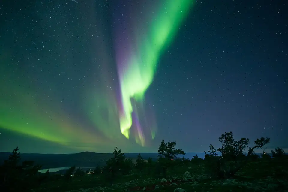 A bright green aurora curtain rising above the trees on Levi fell in Finnish Lapland